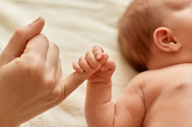 mujer sujetando del dedod a un bebé